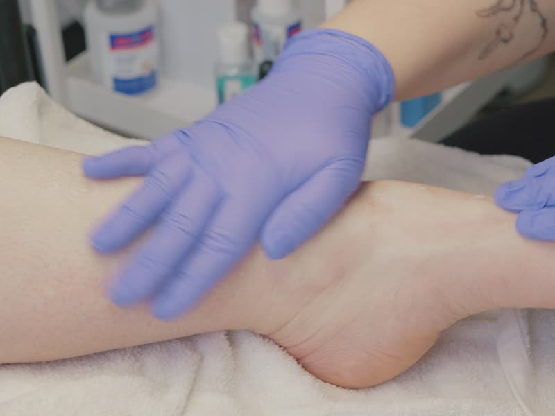 Mains gantées qui massent doucement le pied